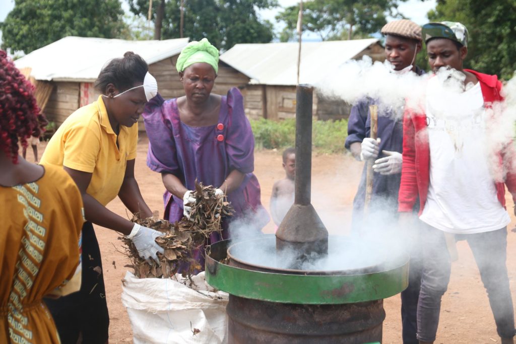 Trainees feeding small scale carbonizer with waste